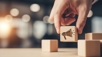 Hand placing a wooden block with a megaphone icon, representing marketing and communication strategy