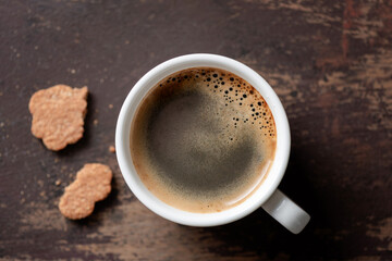 Espresso coffee in white porcelain cup on old wooden table, top view