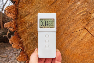 Measuring the radioactivity of wood. Dosimeter radiometer near the trunk of a cut tree. Modern digital device for measuring the level of ionizing radiation