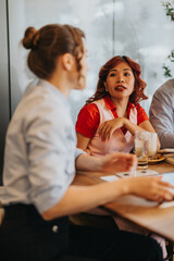 Two colleagues in a bright cafe sit at a wooden table, engaged in a lively discussion about a...