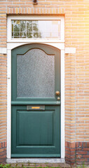 Facade of typical Dutch door house with brick walls, steps, front door windows. Doors on the street, Netherlands