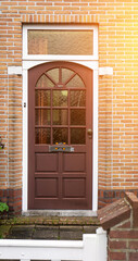 Facade of typical Dutch door house with brick walls, steps, front door windows. Doors on the...