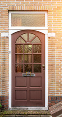 Facade of typical Dutch door house with brick walls, steps, front door windows. Doors on the street, Netherlands