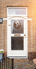 Facade of typical Dutch door house with brick walls, steps, front door windows. Doors on the street, Netherlands
