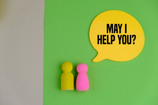 yellow chat memo on green background with two wooden toy on the table with text "May I help you?"
