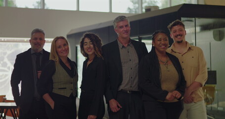 Diverse group of six professionals smiling in modern office space, business team standing together in bright indoor environment with friendly relaxed posture