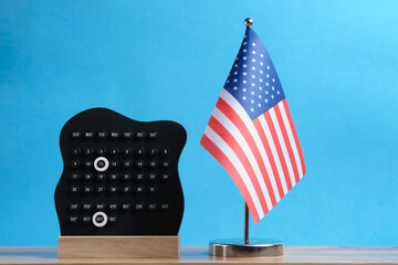 November 11 is Veterans Day. American flag and calendar on table against blue background. Space for text.