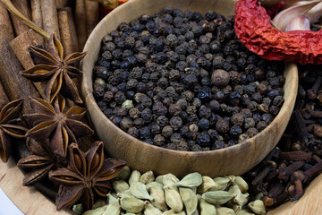 Black pepper and red hot dried pepper in a wooden bowl.