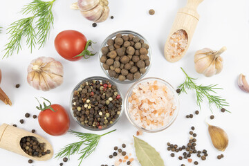 Assortment of spices, fresh vegetables, and herbs on a white background.