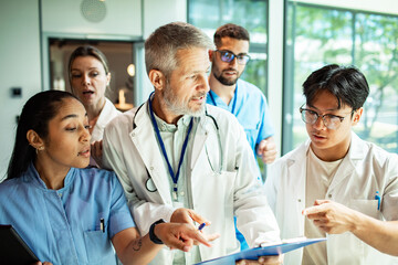 Mature doctor mentoring focused young team in hospital