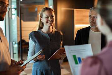 Adult woman smiling while leading team discussion in office