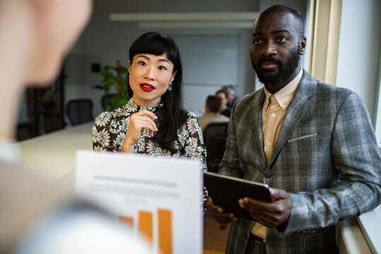 Attentive adult colleagues listening to presentation in modern office