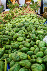 A vibrant display of fresh, green produce at an outdoor market, featuring various fruits and vegetables.