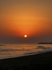 Calm sunrise over an orange sky with gentle waves on a quiet beach