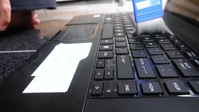 Cleaning a computer keyboard with a brush. Computer maintenance concepts, keeping the device clean
