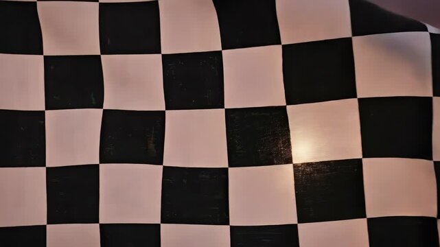Feel the thrill of victory with this dynamic checkered flag waving boldly against a stunning sunset sky, marking ultimate success