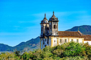 Historic baroque church tower amidst the vegetation and mountains of Ouro Preto