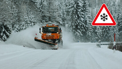 Orange snowplow clearing winter road with caution sign and snow covered forest