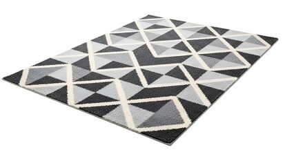 Angled shot of a geometric pattern rug in monochrome shades over a white backdrop