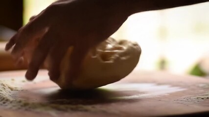 Hand kneading dough on a wooden surface in a home kitchen, flour in background, ideal for recipes