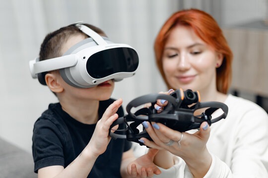 Caucasian woman assisting child with vr headset and drone interaction