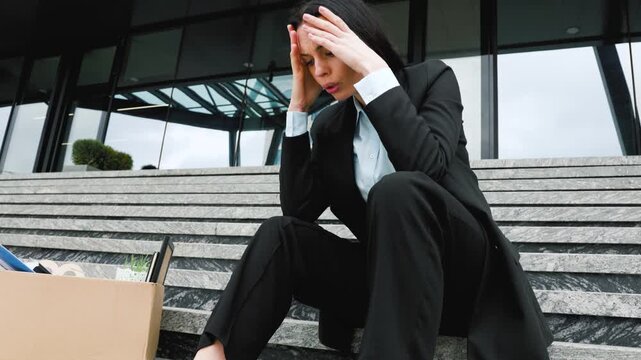 Struggling with Job Loss A Woman Sitting on Stairs with a Cardboard Box