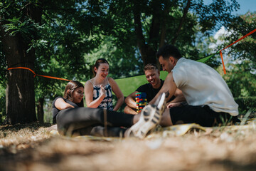 A group of friends relaxes on a sunny day in the park, sharing laughs and a colorful block game. Casual, joyful moment outdoors, capturing friendship and teamwork in a natural setting.