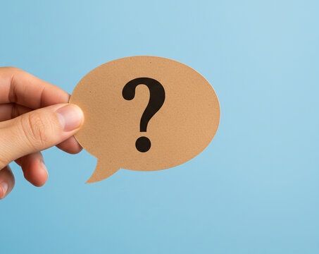 Hand Holding Question Mark Speech Bubble on Blue Background Symbolizing Inquiry and Curiosity, Communication Concept