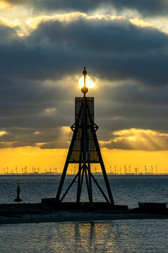 Germany. Elbe River Estuary, Cuxhaven. The silhouette of Kugelbake (historic wooden structure as a day beacon) against the rising sun located at the mouth of the Elbe River