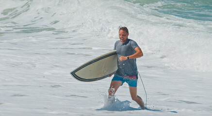 Young surfer walk with surfing boards on the beach in Brazil