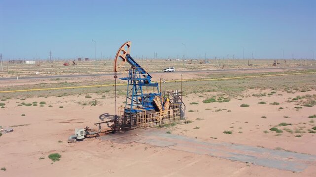 aerial view of desert oil pumpjack and surroundings, remote oil pumpjack operating in desert with maintenance equipment, industrial oil pumpjack in desert environment with service truck and wellhead