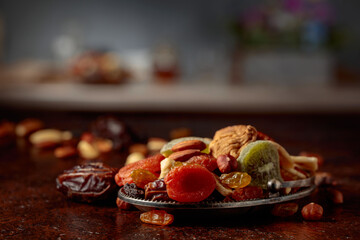 Dried tropical fruits, nuts, and raisins on a kitchen table.