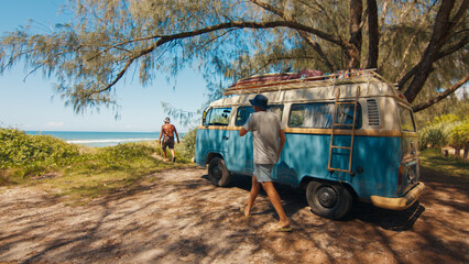 Hippies arrive to the surfing spot by retro classic hippie bus loaded with surfing boards. Hippies travel by retro bus in a search of a surfing spots