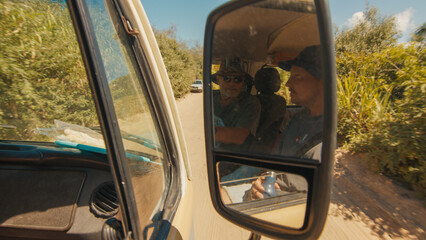 Modern hippie travels on a retro bus. Reflection of a young man in a mirror of a retro car moving on a road