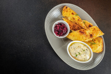 Crispy golden polenta bread served with creamy herb dip and sweet caramelized red onion on an elegant plate dark background copy space for restaurant menu or food advertising