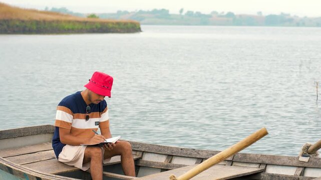 Mans reading the book on small island in sea at sunset, in chacha kota, near Udaipur, Rajasthan, India.