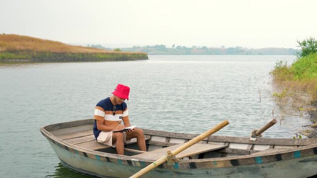 Mans reading the book on small island in sea at sunset, in chacha kota, near Udaipur, Rajasthan, India.
