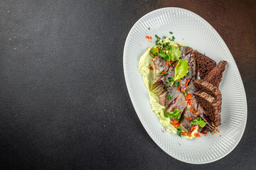 Gourmet herring appetizer served with creamy green sauce, fresh herbs, red onion and dark rye bread, menu, culinary promotions and gourmet food advertising