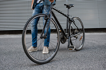 City commuter riding bike on street, holding ball and headphones.