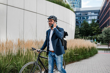 Cyclist making phone call, standing on streeet.