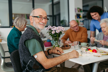 Group of seniors having lunch in community center cafeteria.