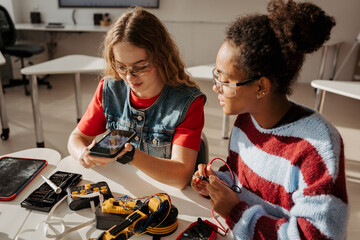 High school students working on robotics project, using online AI app to answer questions.