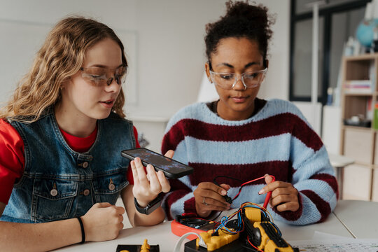 High school students working on robotics project, using online AI app to answer questions.