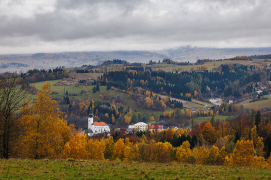Jeseniky mountains at fall season. Overcast above idyllic village Branna, Czech Republic with renaissance church