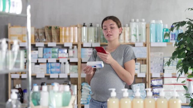 Pregnant woman shopping at pharmacy and scanning ointment barcode on mobile phone. Modern payment methods by QR code. High quality 4k footage