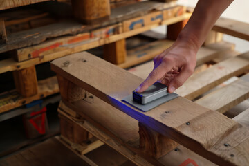 Hand pressing a smart sensor on a wooden pallet for logistics tracking.