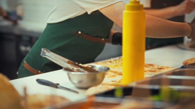A cook is skillfully preparing shawarma at a fast food establishment. Fresh ingredients are being neatly assembled as customers await their delicious meals during the busy lunch rush