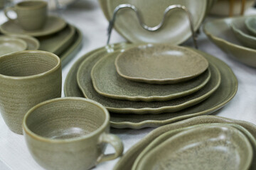 Stacked ceramic plates and cups arranged on table, showcasing various sizes and shapes of dinnerware, closeup highlighting texture and craftsmanship of kitchenware set