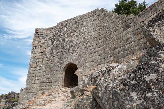 Imponente muralha do castelo de Marialva com um arco no portal da entrada, enquadrado por um alto muro de grandes blocos de pedra r&uacute;stica e rocha em Portugal