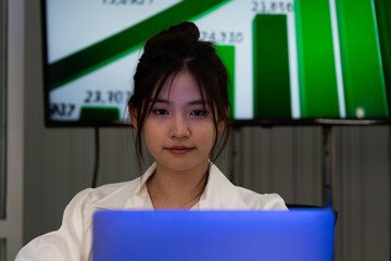 Business team analyzing data on laptops with growth chart in background. Diverse professionals collaborating in office, discussing financial performance, strategy, and success analytics in workplace.